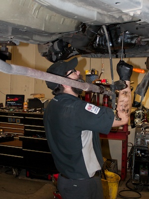 Image of an auto mechanic working on a vehicle on a raised lift