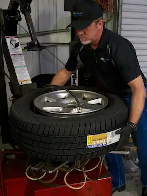 Photo of an auto mechanic using a tire balancing machine at Excalibur Auto Repair in Austin, TX